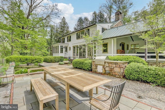 view of patio / terrace with an outdoor kitchen, a grill, a sunroom, and outdoor dining space