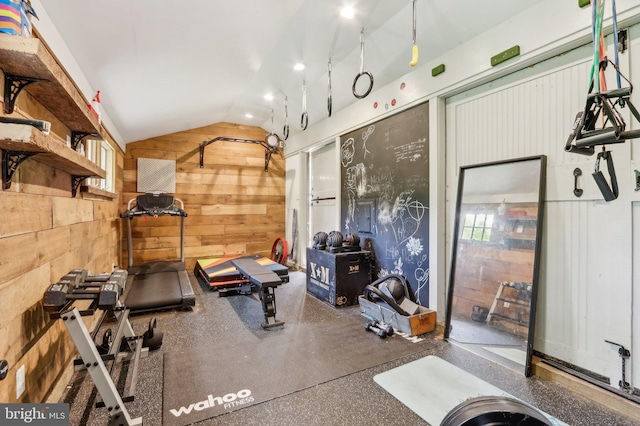exercise room with lofted ceiling and wood walls