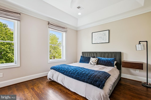 bedroom with visible vents, multiple windows, wood finished floors, and baseboards