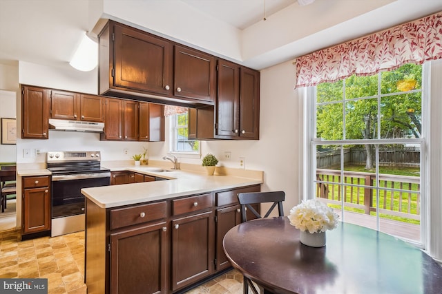 kitchen with a peninsula, light countertops, under cabinet range hood, stainless steel electric stove, and a sink