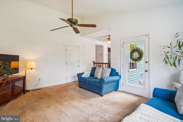 carpeted living area featuring baseboards, ceiling fan, and high vaulted ceiling