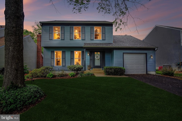 view of front of home featuring a lawn, an attached garage, and driveway