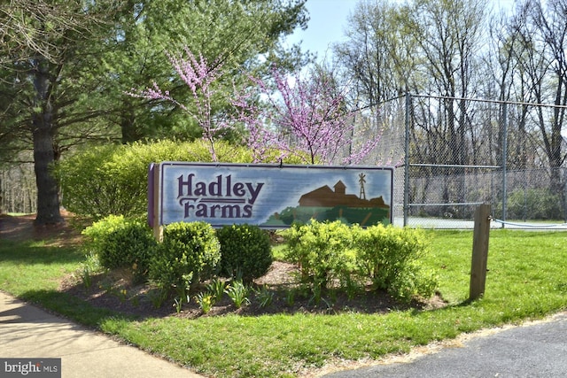 community sign with fence and a lawn
