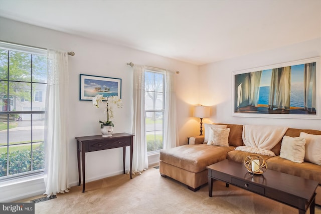 sitting room with baseboards, light colored carpet, plenty of natural light, and visible vents