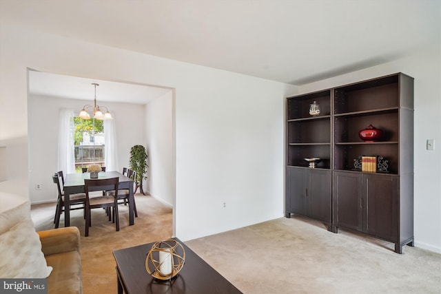 living area featuring light colored carpet and a notable chandelier