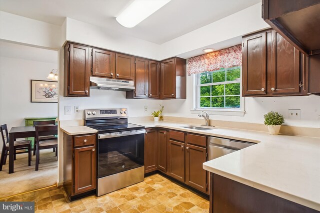 kitchen with stone finish floor, appliances with stainless steel finishes, a sink, light countertops, and under cabinet range hood