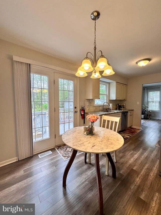 dining room featuring dark wood finished floors, visible vents, a notable chandelier, and plenty of natural light
