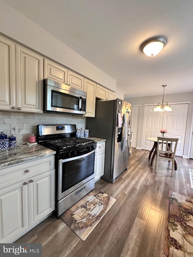 kitchen with an inviting chandelier, hanging light fixtures, stainless steel appliances, backsplash, and dark wood-style floors