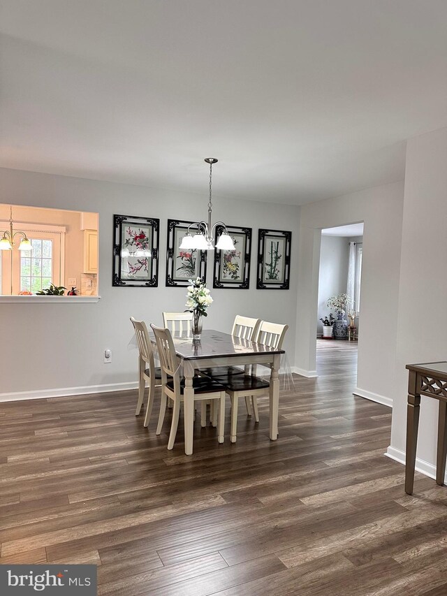 dining room featuring a notable chandelier, baseboards, and dark wood-type flooring