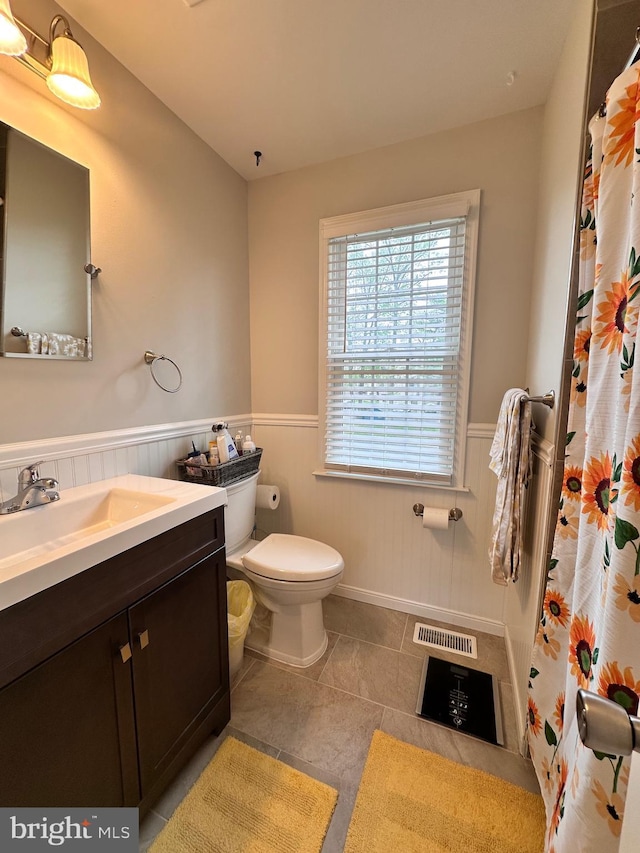 full bath with visible vents, a wainscoted wall, a shower with shower curtain, toilet, and vanity