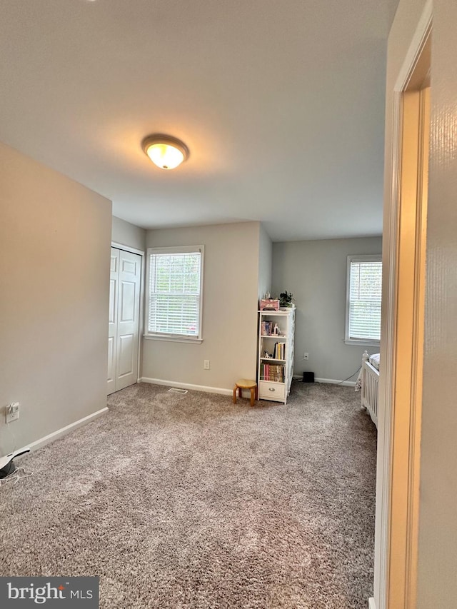 unfurnished bedroom featuring carpet floors, baseboards, and multiple windows