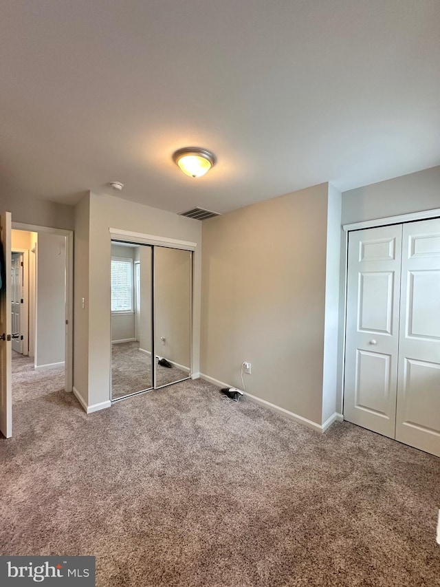 unfurnished bedroom featuring baseboards, visible vents, and carpet