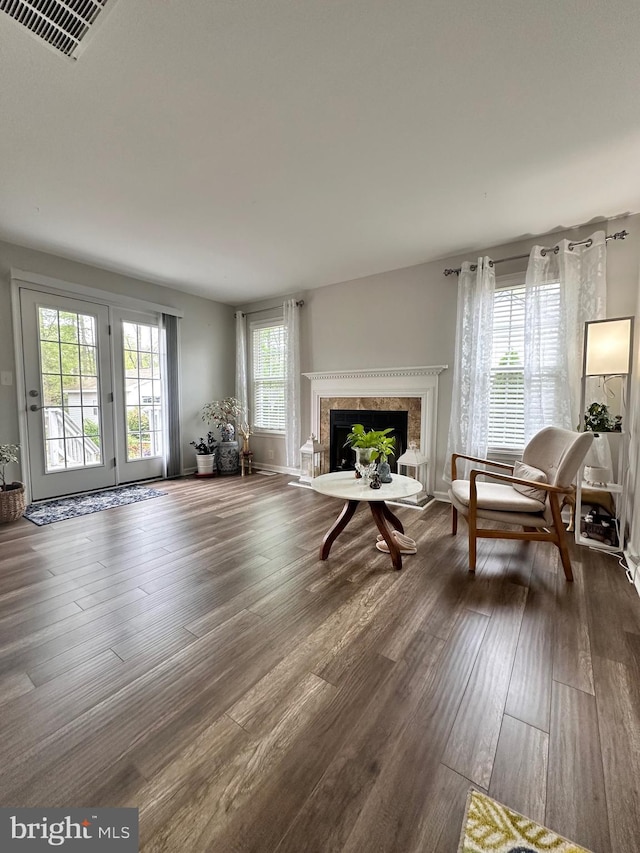 living area featuring dark wood-style flooring, visible vents, and a high end fireplace