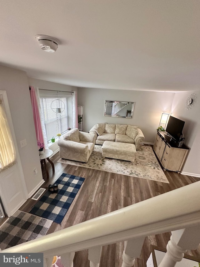living room with wood finished floors, visible vents, and baseboards