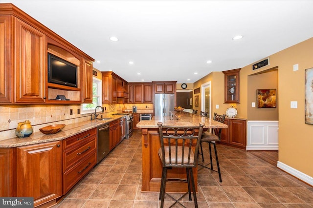 8412 Dasher Ct, Gaithersburg, MD 20882 - kitchen featuring a sink, appliances with stainless steel finishes, a breakfast bar area, light stone countertops, and decorative backsplash