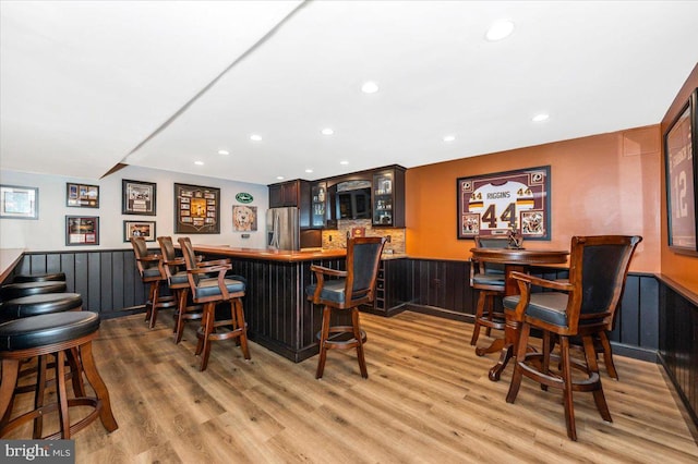 8412 Dasher Ct, Gaithersburg, MD 20882 - indoor wet bar featuring stainless steel fridge, light wood-type flooring, recessed lighting, black microwave, and a wainscoted wall
