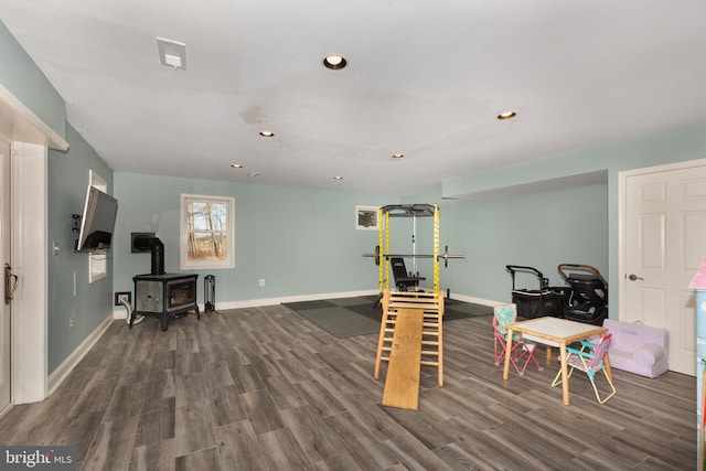 game room with wood finished floors, a wood stove, baseboards, and recessed lighting
