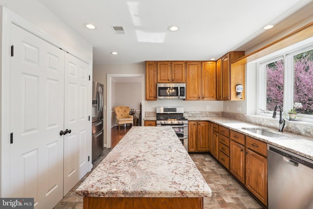 8519 Century Oak Ct, Fairfax Station, VA 22039 - kitchen featuring a kitchen island, visible vents, brown cabinetry, appliances with stainless steel finishes, and a sink