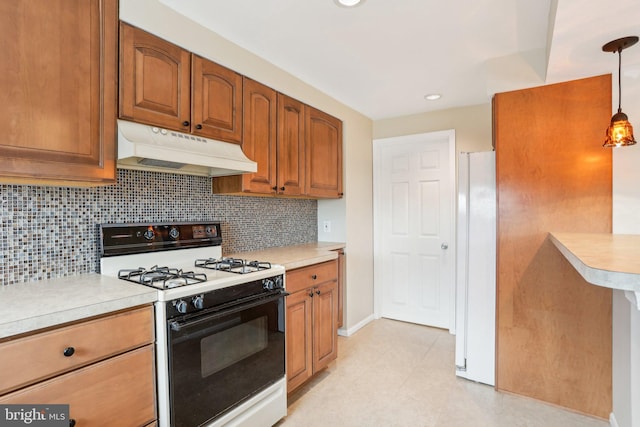 kitchen with under cabinet range hood, light countertops, brown cabinets, and gas range oven