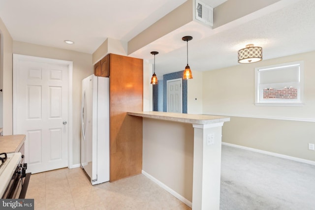 kitchen with freestanding refrigerator, brown cabinets, stove, baseboards, and visible vents