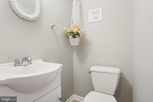 bathroom with baseboards, toilet, and vanity