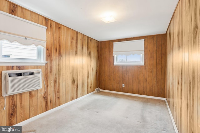 empty room with a wall mounted air conditioner, carpet flooring, visible vents, wooden walls, and baseboards