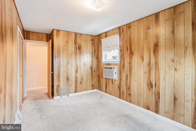 spare room featuring a wall mounted AC, carpet flooring, visible vents, wooden walls, and baseboards