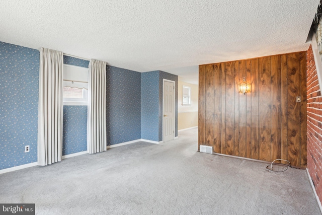 spare room with visible vents, wallpapered walls, and carpet floors