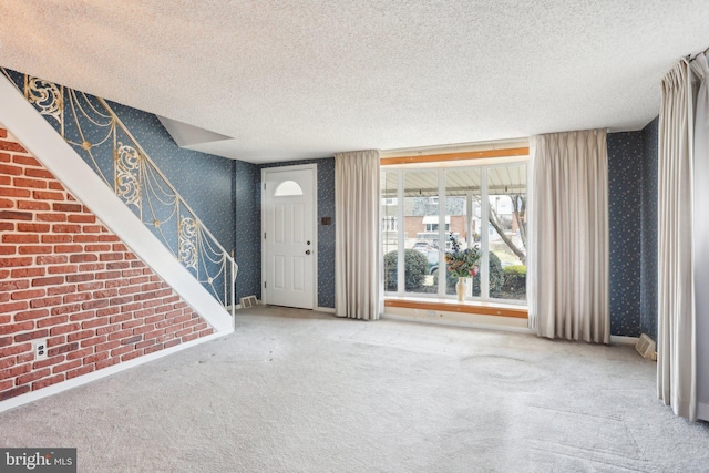 carpeted entrance foyer with baseboards, a textured ceiling, and wallpapered walls