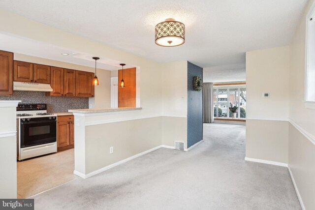 kitchen featuring light colored carpet, gas range oven, under cabinet range hood, decorative backsplash, and visible vents