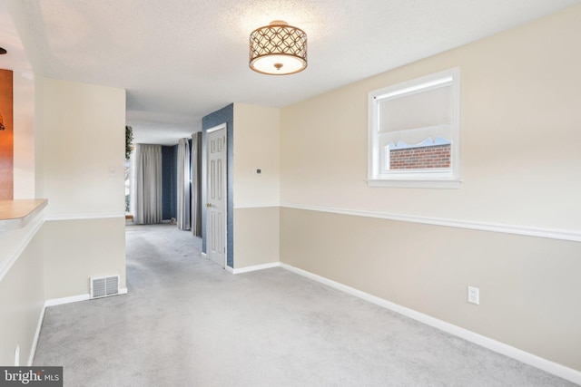 interior space with carpet, baseboards, a textured ceiling, and visible vents
