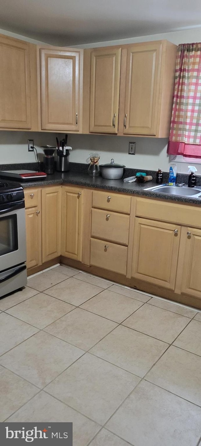 kitchen with light brown cabinets, a sink, stainless steel electric stove, and dark countertops