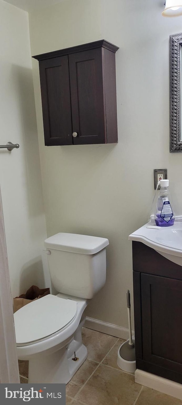half bathroom with tile patterned floors, vanity, baseboards, and toilet