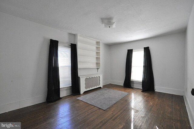 109 N Centre St, Philipsburg, PA 16866 - unfurnished living room with baseboards, a textured ceiling, and dark wood-style flooring