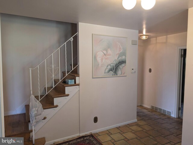 stairway featuring baseboards, visible vents, and stone finish flooring
