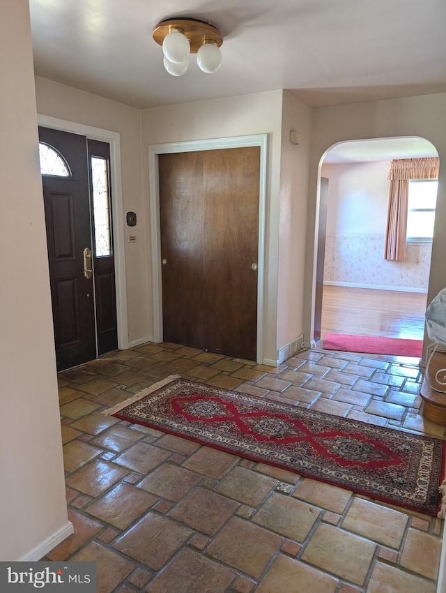 foyer with brick floor, baseboards, and arched walkways