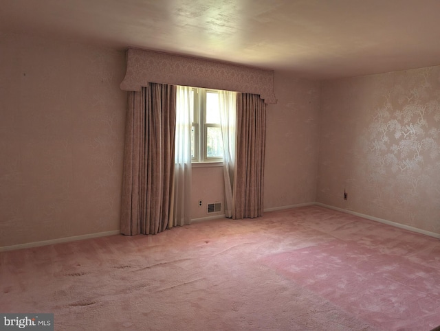 empty room featuring baseboards, visible vents, and carpet floors