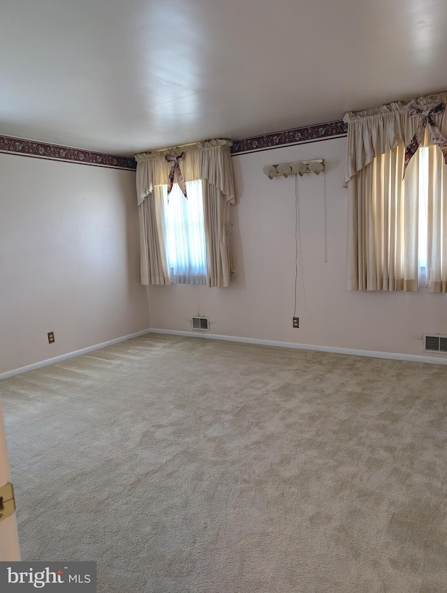carpeted empty room featuring baseboards and visible vents