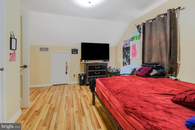 bedroom featuring visible vents, baseboards, vaulted ceiling, and light wood-style floors