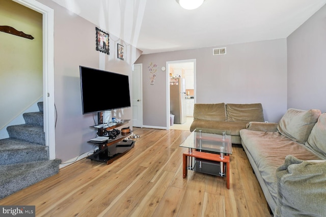 living area featuring stairs, light wood finished floors, and visible vents