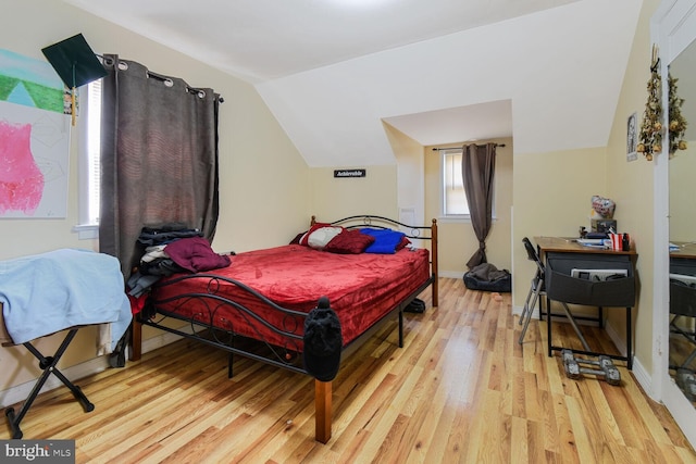 bedroom with baseboards, vaulted ceiling, and wood finished floors
