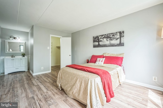 bedroom featuring baseboards, wood finished floors, and a spacious closet