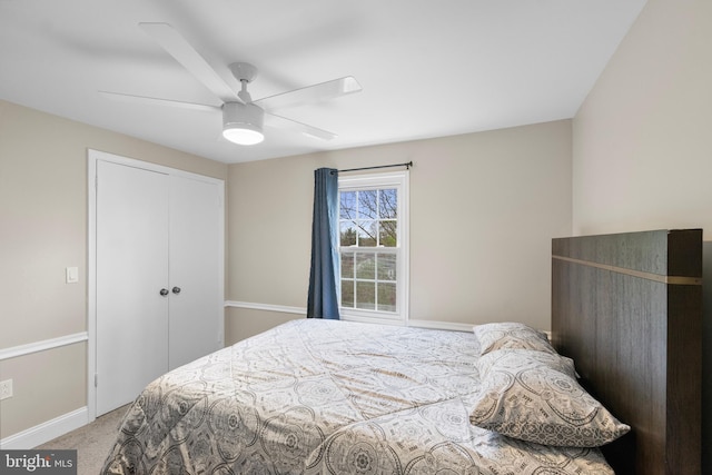 carpeted bedroom featuring a closet, baseboards, and a ceiling fan