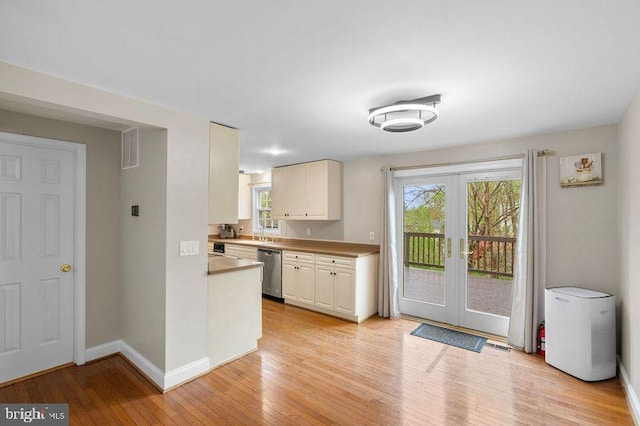 kitchen featuring light wood-type flooring, baseboards, french doors, white cabinetry, and stainless steel dishwasher