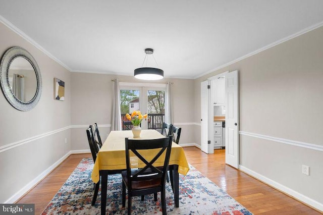 dining space featuring crown molding, light wood-style flooring, and baseboards