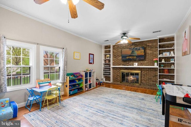rec room with baseboards, visible vents, ceiling fan, built in shelves, and wood finished floors