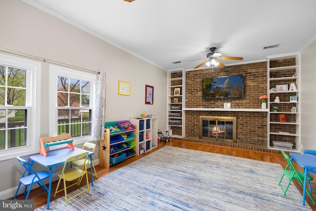 game room featuring ornamental molding, visible vents, ceiling fan, and wood finished floors
