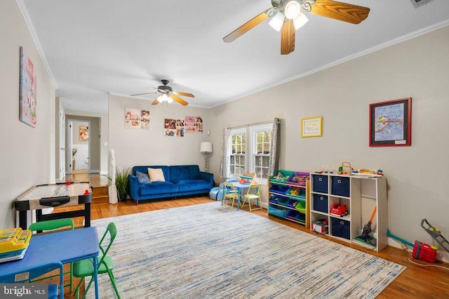 recreation room with wood finished floors, crown molding, and ceiling fan