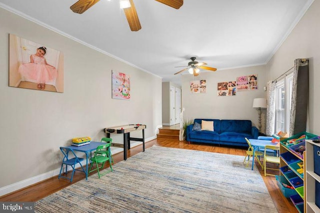 game room featuring wood finished floors, ceiling fan, baseboards, and ornamental molding