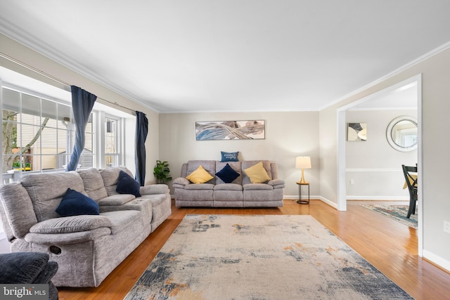 living area with baseboards, ornamental molding, and wood finished floors